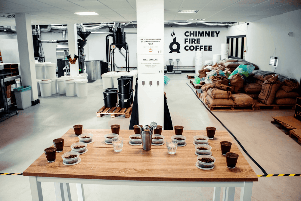 chimney fire coffee roastery cupping table with roaster in background